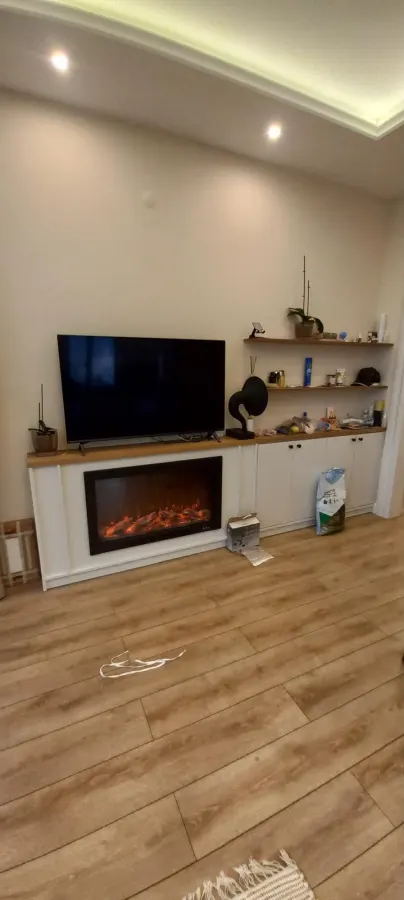 Elektrikli şömineli beyaz TV ünitesi ve meşe raflar